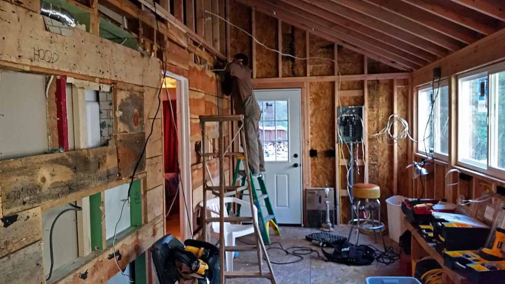 ​electrician and overall view looking toward deck.  Kitchen will be insulated, sheet rocked on the walls after Jon is done, and a ceiling that looks similar to the living room ceiling.  Jon is wiring it so some lighting can be installed on the ceiling and everything will be nicely set up with plugs/switches in the right places. 